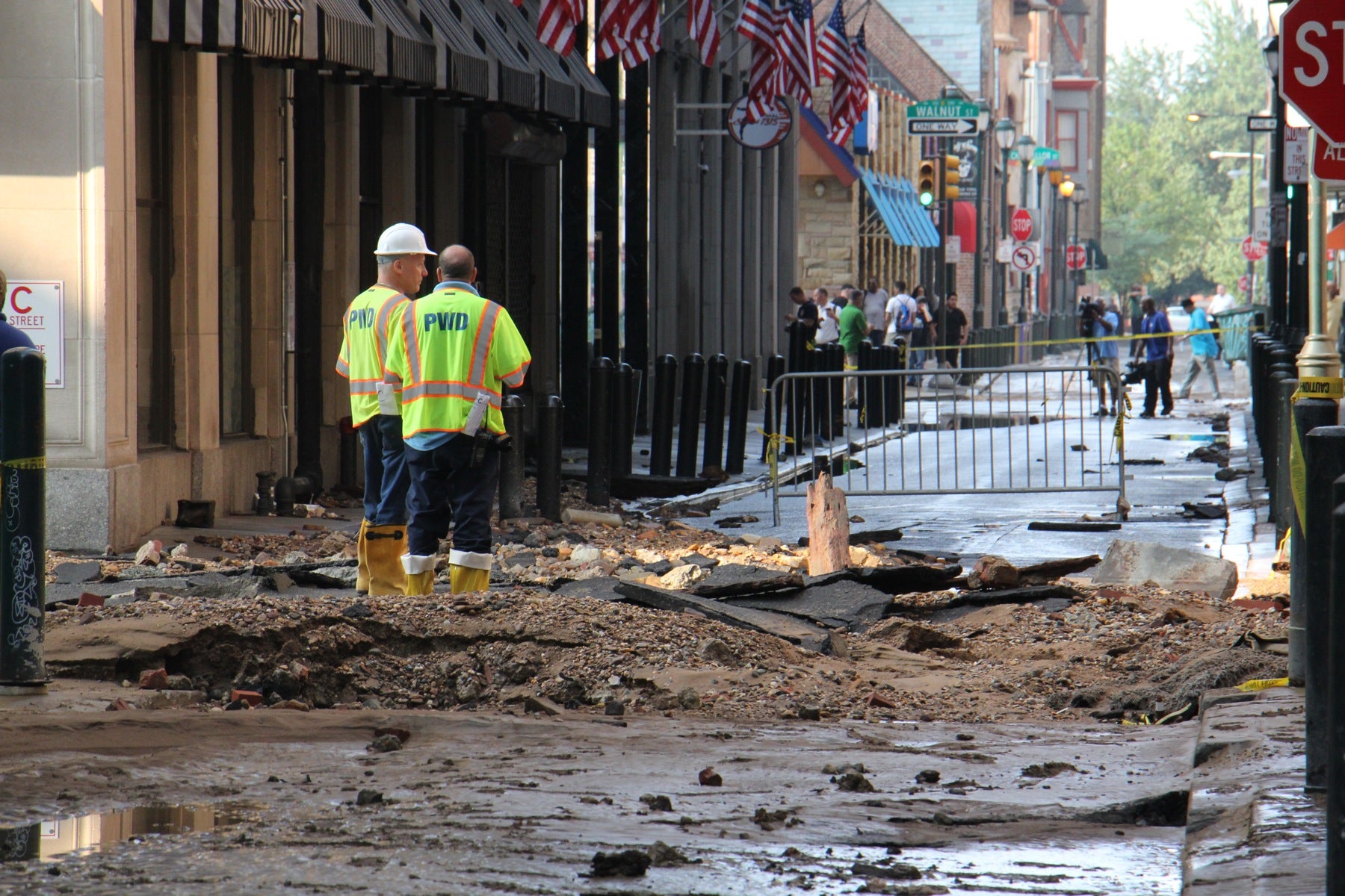 Water department employees stand at the site of the water main break at Sansom and Juniper streets. 