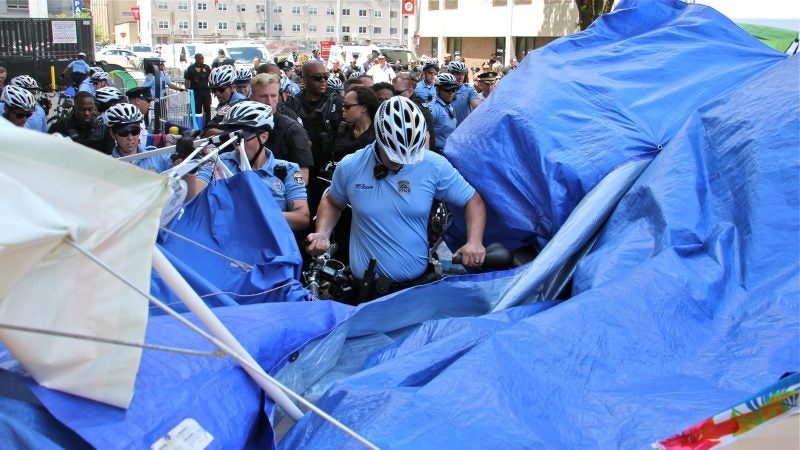 Police use their bicycles to break up a protest encampment outside ICE offices at 8th and Market. (Emma Lee/WHYY)
