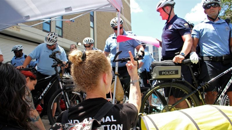 A protester gestures at police before being arrested outside ICE offices at 8th and Cherry streets. (Emma Lee/WHYY)