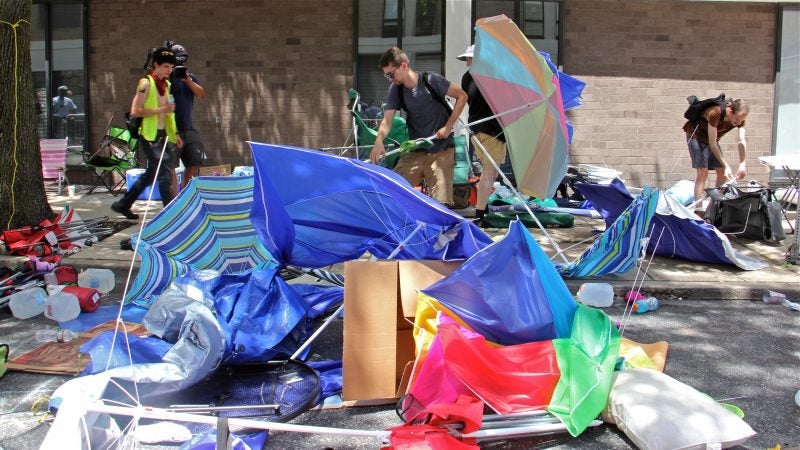 Protesters clean up their campsite on Cherry Street after police swept through. Several were arrested, and police left behind a reconfigured campsite that keep the entrances to ICE offices clear. (Emma Lee/WHYY)