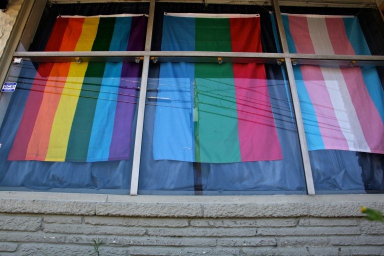 Flags hang in the windows of the headquarters of Feminist Apparel in Somerdale, New Jersey. (Emma Lee/WHYY)