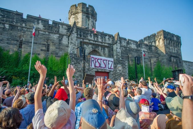 People in the crowd reach for the sky as Marie Antoinette and her minions throw Tastykakes from the top of the Eastern State Penitentiary wall.