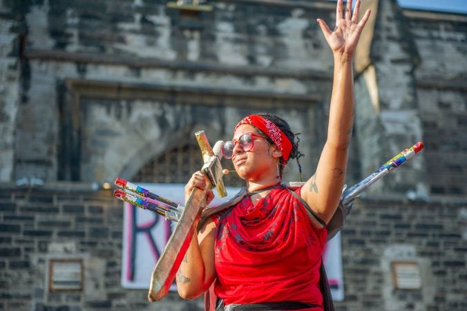 With her mobile phone taped to her sword, Jackie Soro, portraying Joan of Arc, calls Pennsylvania Senator Pat Toomey's office to let her feelings be known. (Jonathan Wilson for WHYY)