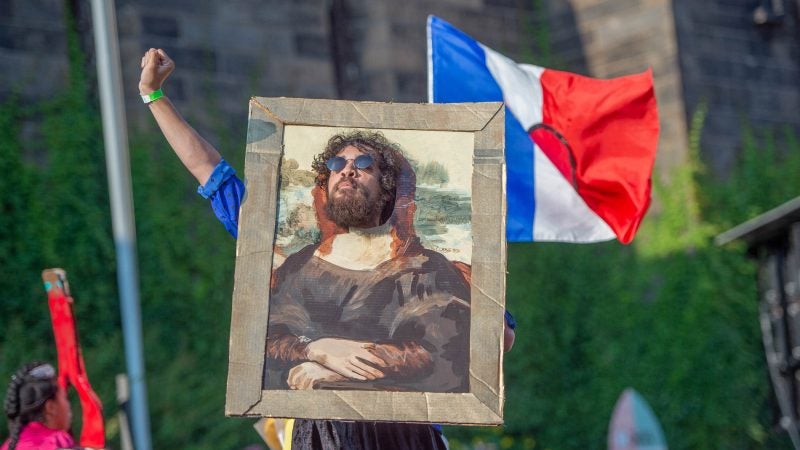 Anthony Martinez-Briggs inserts his head into a rendering of the Mona Lisa during one of the cabaret numbers. (Jonathan Wilson for WHYY)