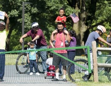A group of immigrants detained at the Berks County Residential Center in Leesport, Pennsylvania, respond to a protest of the detention center occurring across the street from the facility on the afternoon of July 15. On the left, a man holds a handmade drawing of the Honduran flag. (Rachel Wisniewski for WHYY)