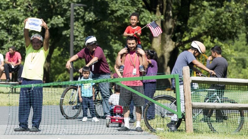 A group of immigrants detained at the Berks County Residential Center in Leesport, Pennsylvania, respond to a protest of the detention center occurring across the street from the facility on the afternoon of July 15. On the left, a man holds a handmade drawing of the Honduran flag. (Rachel Wisniewski for WHYY)