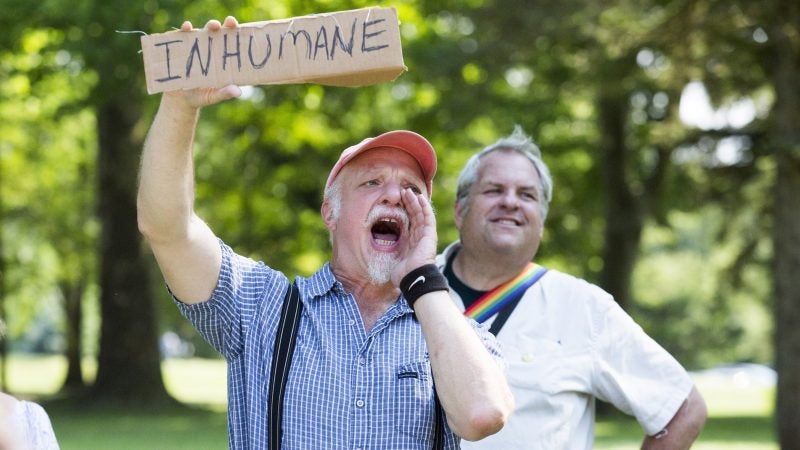 A protester yells to nearby police officers, asking 