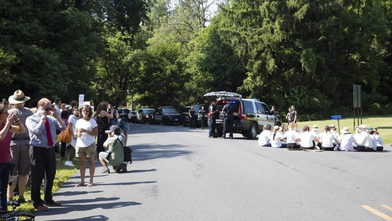 About 200 protesters hold a vigil outside the Berks County Residential Center in Leesport. Despite being told that they would risk arrest if they stepped out into the street, eighteen demonstrators decided to sit in the road. Police officers stand by. (Rachel Wisniewski for WHYY)