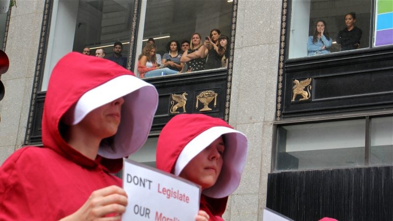 Spectators watch the protest from second story windows across the street from the Union League, where Vick President Mike Pence was speaking. (Emma Lee/WHYY)