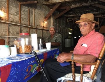 Bufus Outlaw, 93, (right) and Theodore Jackson, 83, hang out in Outlaw's garage in Gray's Ferry. Although they weren't alive for the 1918 riots, they have seen the results ripple through their neighborhood to the present.