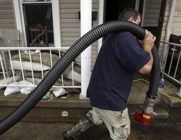 A volunteer hauls a hose past flooded homes as he and others help pump water out Wednesday, July 25, 2018, in Tremont, Pa. Days of drenching rains are closing roads, sending creeks and streams over their banks and prompting some evacuations in central Pennsylvania. (Jacqueline Larma/AP Photo)