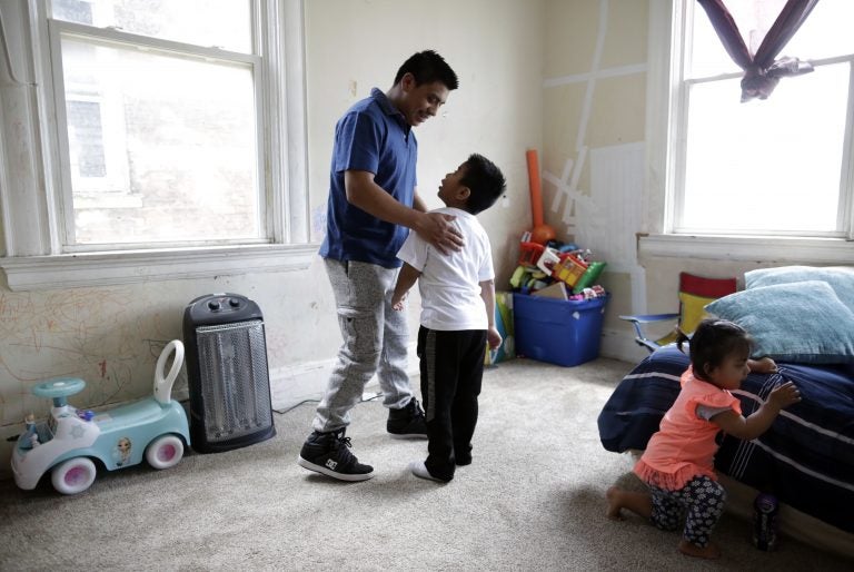 Edgar Perez Ramirez, left, stands with his 4-year-old son, Franco, in their home in Covington, Ky., on April 28, 2018. Perez left San Marcos, Guatemala, for Kentucky after his father was killed. He was heading to work when agents stopped and arrested him in December. (AP Photo/Gregory Bull)