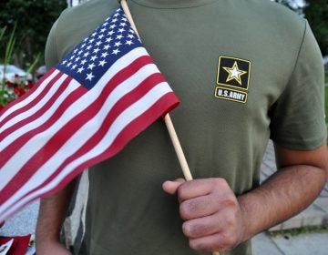 A Pakistani recruit, 22, who was recently discharged from the U.S. Army, holds an American flag as he poses for a picture. The man asked his name and location to be undisclosed for safety reasons. The AP interviewed three recruits from Brazil, Pakistan and Iran, all of whom said they were devastated by their unexpected discharges. (AP Photo/Mike Knaak)