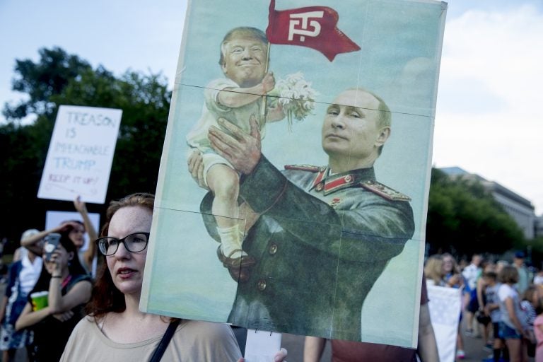 A woman holds a sign depicting Russian President Vladimir Putin and President Donald Trump during a protest outside the White House following Trump's meetings with Putin. (Andrew Harnik/AP Photo)