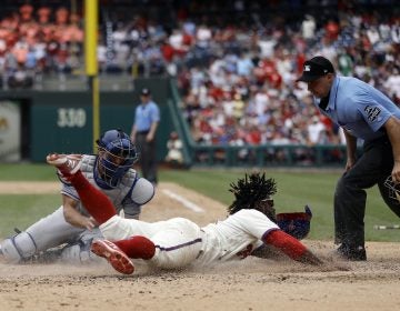 Philadelphia Phillies' Odubel Herrera, center, scores past Los Angeles Dodgers catcher Austin Barnes, left, on a three-run triple by Carlos Santana during the fifth inning of a baseball game, Wednesday, July 25, 2018, in Philadelphia. At right is umpire Adam Hamari. (AP Photo/Matt Slocum)