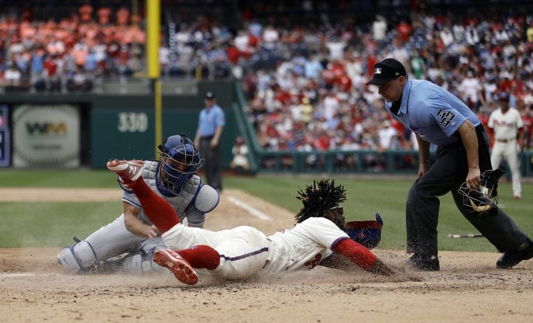 Philadelphia Phillies' Odubel Herrera, center, scores past Los Angeles Dodgers catcher Austin Barnes, left, on a three-run triple by Carlos Santana during the fifth inning of a baseball game, Wednesday, July 25, 2018, in Philadelphia. At right is umpire Adam Hamari. (AP Photo/Matt Slocum)