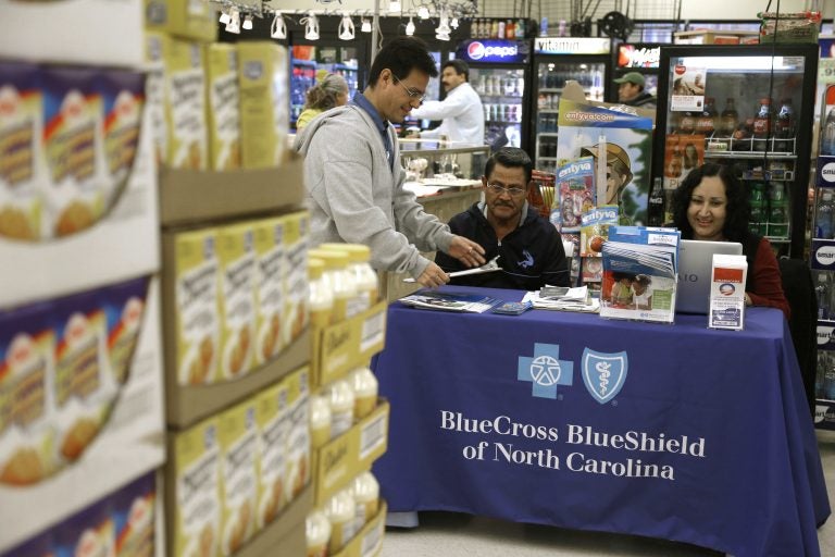 In this file photo taken Nov. 22, 2014, Blue Bridge Benefits LLC agent Patricia Sarabia, right, and Adolfo Briceno, left, with Spanish Speaking LLC, help a potential customer with Blue Cross Blue Shield at a kiosk promoting Obama Care at Compare Foods in Winston-Salem, N.C. A new poll finds that more than half of Hispanic adults have encountered a communication barrier in the health care system. (AP Photo/Gerry Broome, file)