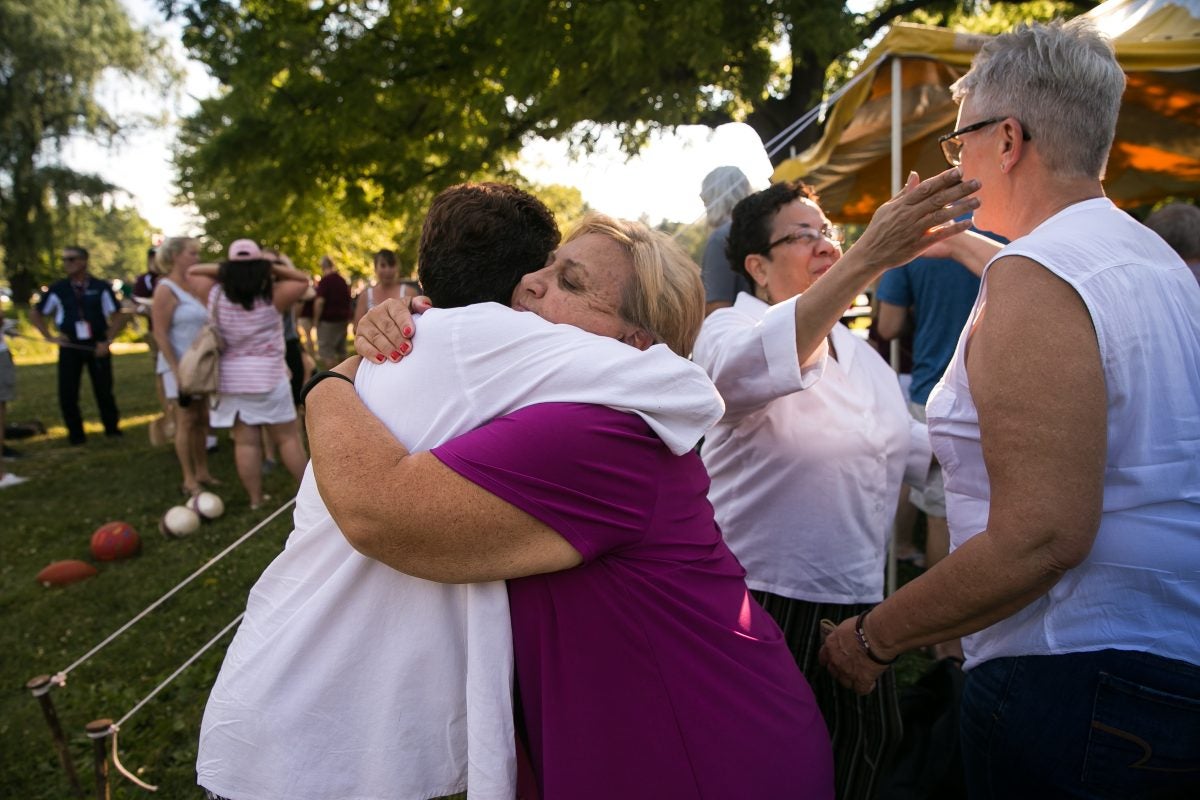 Alumni Linda Riley, left, receives a hug from Cheryl Gillick, center, as Lee Ann Riley, second from right, receives a hug from Laura Masker, far right, at a Cadets alumni picnic Saturday. The twins have both accused Hopkins of abuse.