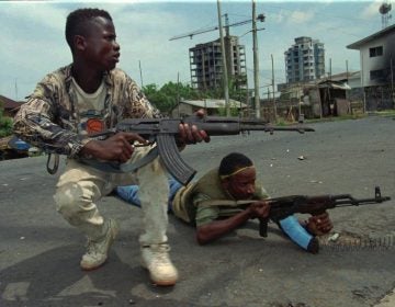 Fighters from the United Liberation Movement of Liberia (ULIMO) shoot their way through downtown Monrovia, LIberia Tuesday, April 16, 1996. (AP Photo/Jean-Marc Bouju)