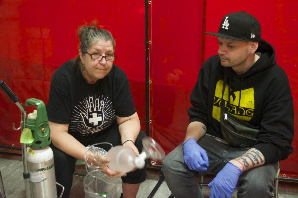Sue Ouellette trains a new Molsen Overdose Prevention Site peer in using the oxygen tank and breathing mask. Photo by Elana Gordon/WHYY