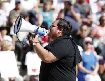 Victor Galvan uses a bullhorn to lead chants during an immigration rally and protest in Civic Center Park Saturday, June 30, 2018, in downtown Denver. The protest was one of hundreds staged nationwide that has brought liberal activists, parents and first-time protesters--motivated by accounts of children separated from their parents at the US-Mexico border--to press President Donald Trump to reunite families quickly. (AP Photo/David Zalubowski)