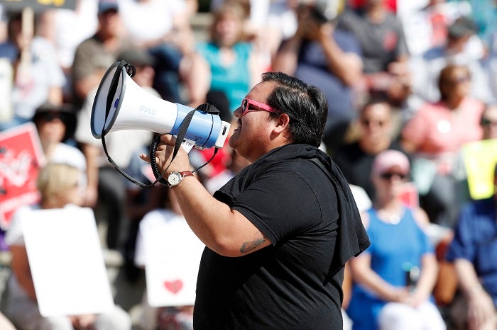 Victor Galvan uses a bullhorn to lead chants during an immigration rally and protest in Civic Center Park Saturday, June 30, 2018, in downtown Denver. The protest was one of hundreds staged nationwide that has brought liberal activists, parents and first-time protesters--motivated by accounts of children separated from their parents at the US-Mexico border--to press President Donald Trump to reunite families quickly. (AP Photo/David Zalubowski)
