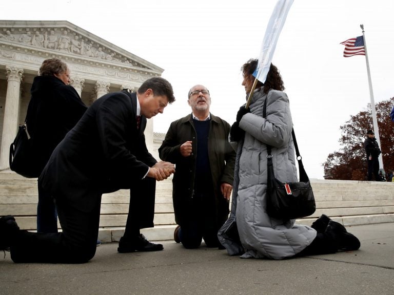 The Rev. Brad Wells, left, the Rev. Patrick Mahoney and Paula Oas, kneel in prayer in front of the Supreme Court, as the court hears the Masterpiece Cakeshop case. (Jacquelyn Martin/AP)