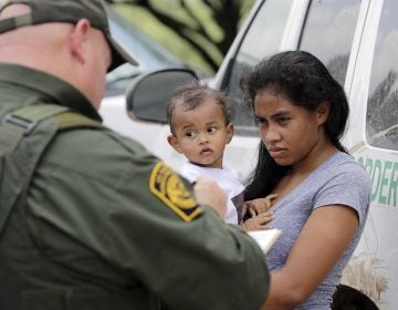 A mother migrating from Honduras holds her 1-year-old child as she surrenders to a U.S. Border Patrol agents after illegally crossing the border, near McAllen, Texas, in late June.