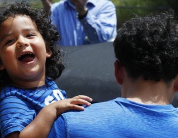 Ever Reyes Mejia, of Honduras, carries his son to a vehicle after being reunited and released by United States Immigration and Customs Enforcement in Grand Rapids, Mich. (Paul Sancya/AP)