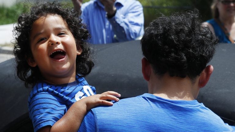 Ever Reyes Mejia, of Honduras, carries his son to a vehicle after being reunited and released by United States Immigration and Customs Enforcement in Grand Rapids, Mich. (Paul Sancya/AP)