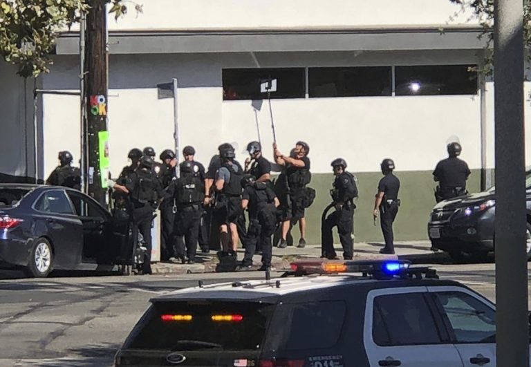 Police officers use a mirror to see inside a Trader Joe's store in the Silver Lake neighborhood of Los Angeles on Saturday. Police believe a man involved in the standoff with officers shot a young female and his grandmother before firing at officers during a pursuit, then crashing outside the supermarket and running inside the store. (Christian Dunlop/AP)