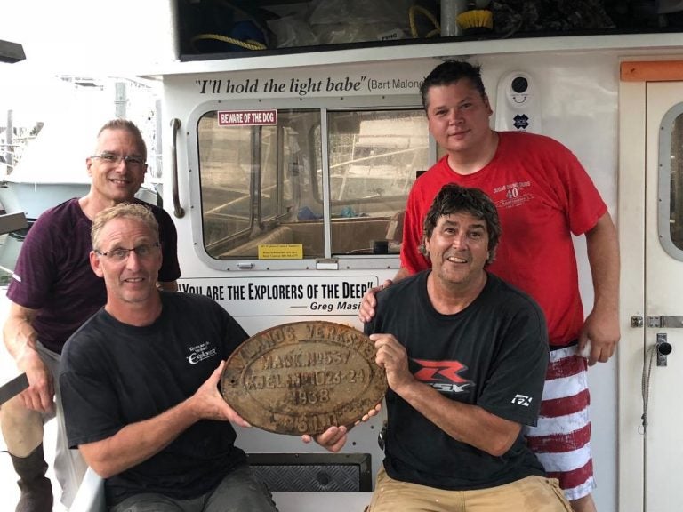 Dive Crew shows off the plate from boat sunk by German U-boats during World War II. Top Left Tom Packer, Bottom Left Rustin Cassway, Top Right, Mike Dudas, Bottom Right Brian Sullivan (Photo courtesy of Rustin Cassway)