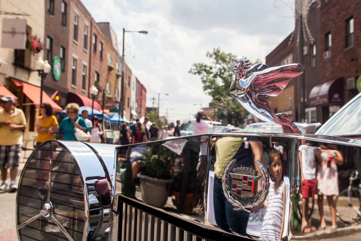 The chrome on a vintage Cadillac reflects the crowd at the Passyunk Avenue Car Show and Street Festival.