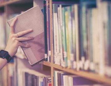 Student picking book from bookshelf at university (bigstockphoto.com)