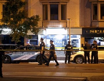 Police officers walk the scene in the Greektown neighborhood of Toronto Sunday night. Police say a gunman opened fire on 14 people in a restaurant. Three people are dead including the gunman, police reported. (Cole Burston/AFP/Getty Images)