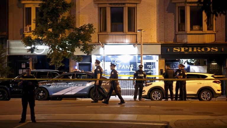 Police officers walk the scene in the Greektown neighborhood of Toronto Sunday night. Police say a gunman opened fire on 14 people in a restaurant. Three people are dead including the gunman, police reported. (Cole Burston/AFP/Getty Images)