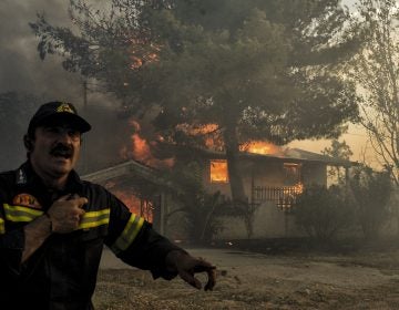 A firefighter next to a house burning during a wildfire in Kineta, near Athens, Greece, on Monday. Wildfires are not new to Greece but several blazes erupted especially quickly. (Valerie Gache/AFP/Getty Images)