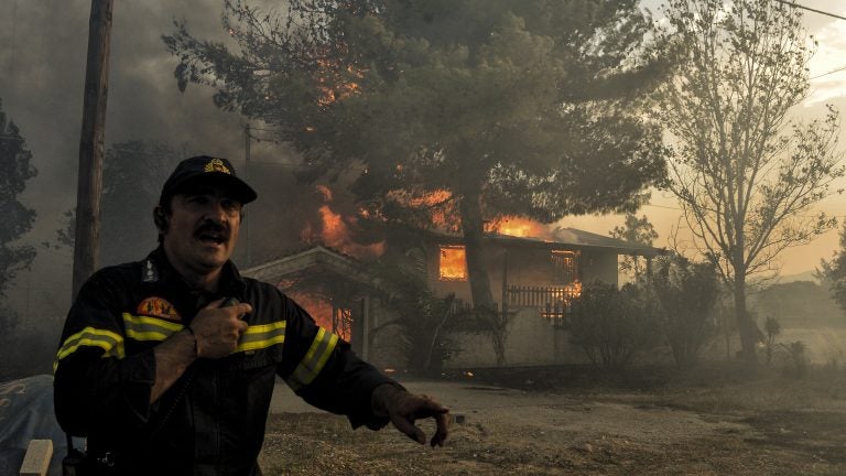 A firefighter next to a house burning during a wildfire in Kineta, near Athens, Greece, on Monday. Wildfires are not new to Greece but several blazes erupted especially quickly. (Valerie Gache/AFP/Getty Images)