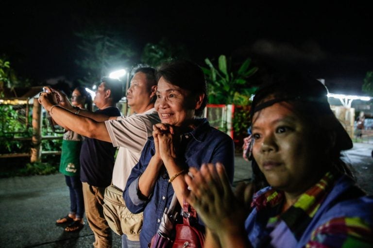 Onlookers watch and cheer as ambulances deliver boys rescued from a cave in northern Thailand to a hospital in Chiang Rai on Sunday.