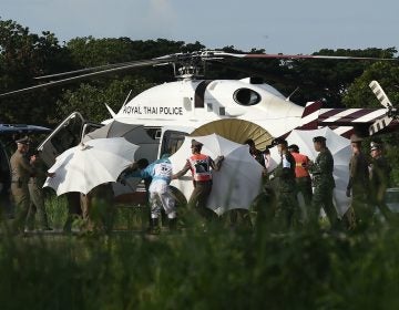 Police and military personnel use umbrellas to cover a stretcher as it is carried to a helicopter from an ambulance at a military airport in Chiang Rai, Thailand, on Monday, as rescue operations continue for those still trapped inside the cave in Khun Nam Nang Non Forest Park in the Mae Sai district.