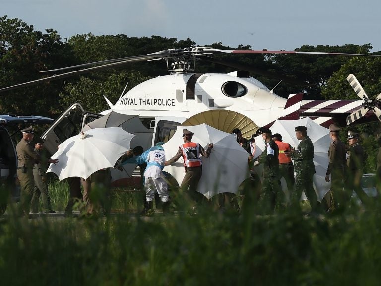 Police and military personnel use umbrellas to cover a stretcher as it is carried to a helicopter from an ambulance at a military airport in Chiang Rai, Thailand, on Monday, as rescue operations continue for those still trapped inside the cave in Khun Nam Nang Non Forest Park in the Mae Sai district.