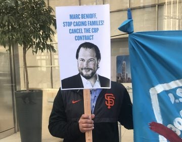 A protester holds up a sign targeting Salesforce CEO Marc Benioff outside the company's headquarters in San Francisco on Monday.
(Laura Sydell/NPR)