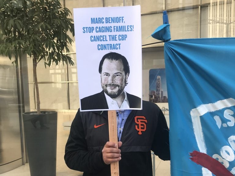 A protester holds up a sign targeting Salesforce CEO Marc Benioff outside the company's headquarters in San Francisco on Monday.
(Laura Sydell/NPR)