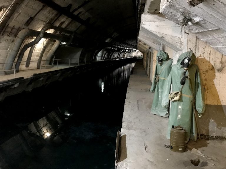 Hazmat suits hang next to the canal that leads from Balaklava Bay to the heart of the underground base. (Lucian Kim/NPR)