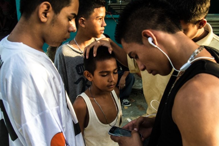 A group of older boys, some of whom are gang members, joke around with a younger boy. Neighborhood children are often groomed for gang activity from the age of 6 or 7. At first they may be given small assignments — like buying snacks for gang members or monitoring who's coming in and out of a neighborhood, says Ayuso. Bit by bit, he says, they graduate into bigger responsibilities. (Tomas Ayuso)
