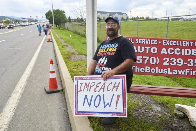 Scott Buchanan, of Quakertown, Pa., came to Wilkes-Barre to protest President Trump on August 2, 2018. He sits at the entrance of the Mohegan Sun Arena as Trump supporters walk towards the Make America Great Again rally. (Natalie Piserchio for WHYY)