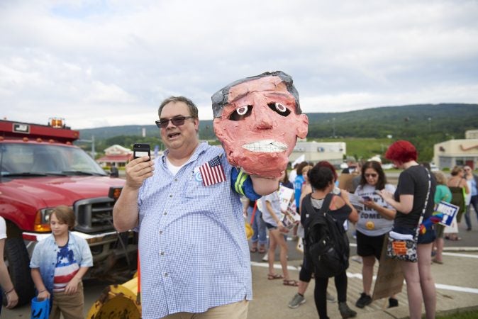 Dwayne Heisler holds a paper mache Lou Barletta head at an Anti-Trump protest outside of the Make America Great Again rally in Wilkes-Barre on August 2, 2018. (Natalie Piserchio for WHYY)