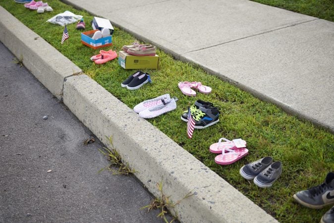 Children's shoes are seen lined up along the sidewalk during the Anti-Trump protest held outside of the Make America Great Again rally in Wilkes-Barre, Pa. on August 2, 2018. (Natalie Piserchio for WHYY)