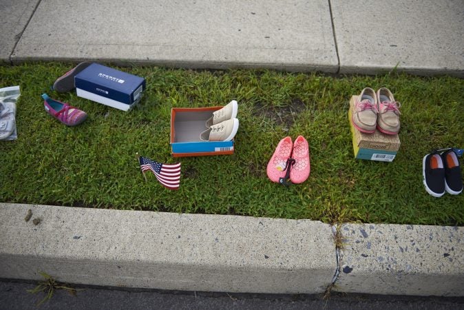 Children's shoes are seen lined up along the sidewalk during the Anti-Trump protest held outside of the Make America Great Again rally in Wilkes-Barre, Pa. on August 2, 2018. (Natalie Piserchio for WHYY)