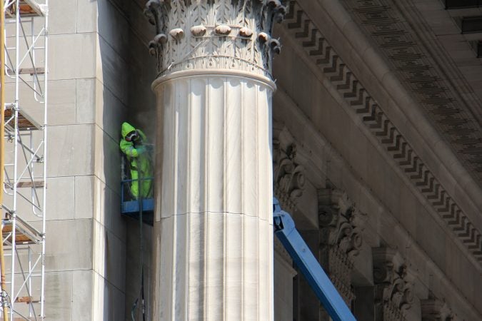 A worker cleans a column of the East Portico at 30th Street Station. (Emma Lee/WHYY)